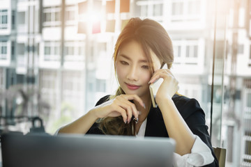 business woman using phone and laptop computer in office.