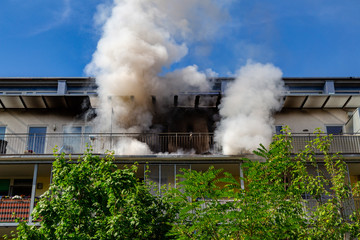 ein Wohnungsbrand in einem Hochhaus, viel Qualm auf dem Balkon