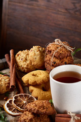 Conceptual festive composition with a cup of hot tea, cookies and spicies on a wooden barrel, selective focus, close-up