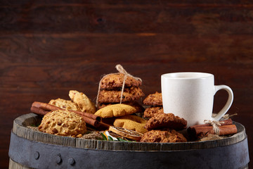 Conceptual festive composition with a cup of hot tea, cookies and spicies on a wooden barrel, selective focus, close-up