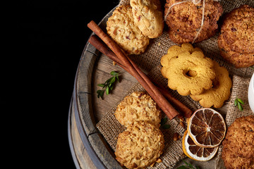 Conceptual festive composition with a cup of hot tea, cookies and spicies on a wooden barrel, selective focus, close-up