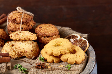 Conceptual composition with assortment of cookies and cinnamon on a wooden barrel, selective focus, close-up