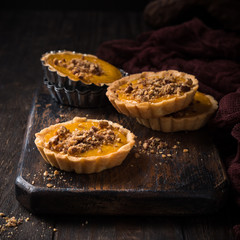 Pumpkin mini pie, tartlet made for Thanksgiving day on old wooden background. Healthy autumn food...