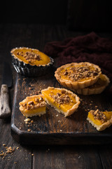 Pumpkin mini pie, tartlet made for Thanksgiving day on old wooden background. Healthy autumn food concept with copy space. Dark photo.