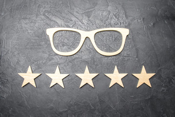 Wooden glasses and five stars on a concrete background. High quality glasses. The best optics....