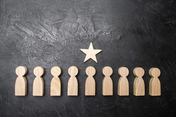 A star above a person who stands in a row among other people. Wooden figurines. The concept of a...