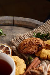 White porcelain mug of tea and sweet cookies on wooden background, top view, selective focus