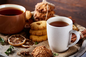 White porcelain mug of tea and sweet cookies on wooden background, top view, selective focus