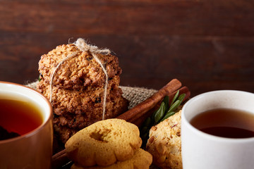 Christmas concept with a cup of hot tea, cookies and decorations on a log over wooden background, selective focus