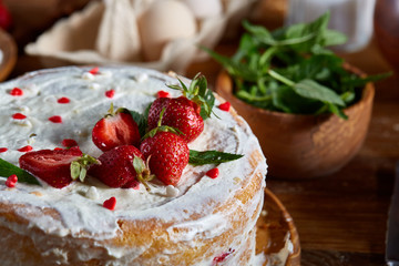 Strawberry tart covered with whipped sour cream on a wooden tray over rustic background, selective focus