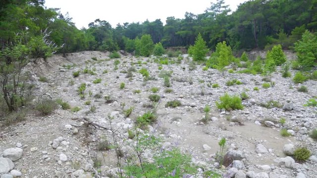 Beautiful cloudy scenic landscape. Dry stony bottom of river in forest. Camera moving from left to right. Taurus mountains in Turkey, Beldibi, between Kemer and Antalya turkish cities in background.