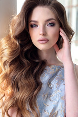 beautiful woman with dark hair in elegant dress walking on the street in summer city