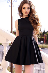beautiful woman with dark hair in elegant dress walking on the street in summer city