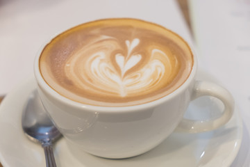 Latte art coffee on the wood table.