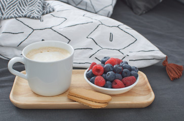 Breakfast bed Wooden tray Hotel room Early morning Concept interior Copy space Geometric sheet and pillow case Berries Cappuccino cup Biscuits