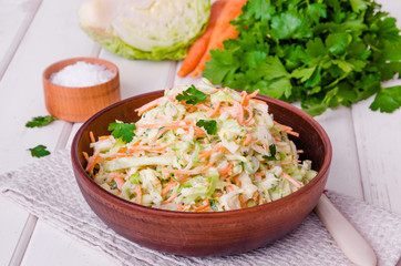Fresh coleslaw salad in bowl on white wooden background.