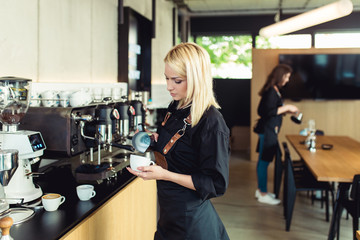 Female barista making espresso coffee.