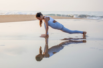 Caucasian woman practicing yoga at seashore of tropic ocean
