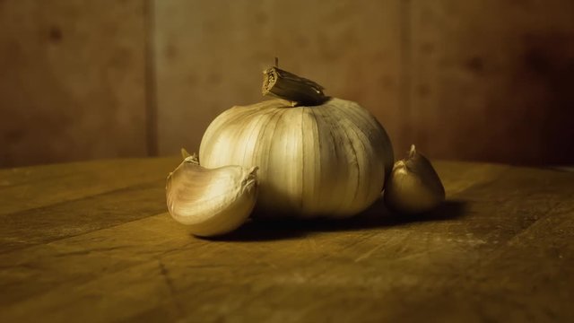 Head of garlic and cloves of garlic on wooden desk. Rotating, turntable shot. Still life