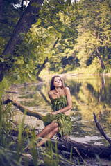 Summer heat. Beautiful young girl in a forest lake, open clothes from fern leaves, perfectly combined with nature. A person in the form of a fantasy elf, dryads, cosplay of a character.