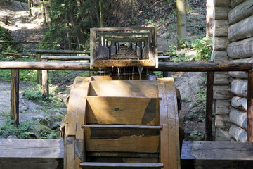Working water mill wheel with falling water in the village. Sustainable energy and water power traditional machinery