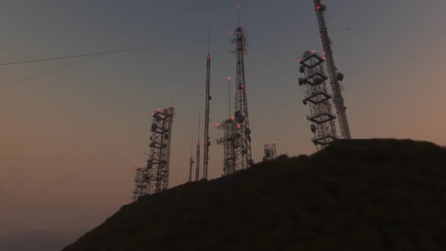 Loopable camera spin around an antenna complex on a hill during sunset. 4k