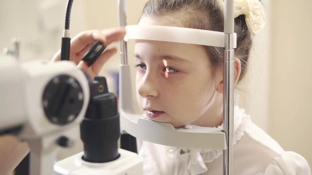 portrait of a girl who checks the cornea of her eye with an ophthalmologist, the child does the procedure Biomicroscopy of the eye in the office of the oculist