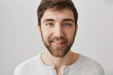 Fototapeta premium Guy assures you would not regret meeting him. Studio shot of handsome confident caucasian man with beard smiling sensually and looking at camera as if checking out hot woman, standing over gray wall