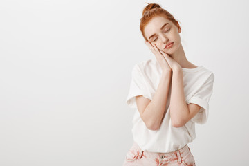 Just give me sec to sleep. Portrait of calm and cute natural redhead female in stylish modern outfit, leaning on palms as if sleeping with closed eyes, dreaming, being tired after university