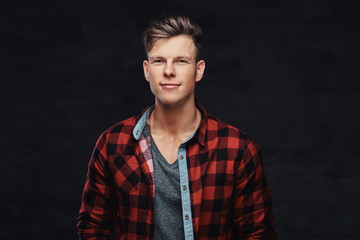 Portrait of a smiling fashionable young guy in a fleece shirt, posing at a studio.