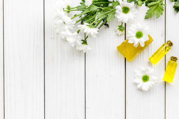 Cosmetics for skin care with chamomile. Oil, soap on white wooden background top view copy space