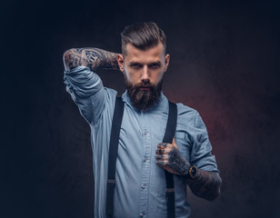 Portrait of a handsome old-fashioned hipster in a blue shirt and suspenders.