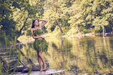 Fototapeta na wymiar Summer heat. Beautiful young girl in a forest lake, open clothes from fern leaves, perfectly combined with nature. A person in the form of a fantasy elf, dryads, cosplay of a character.