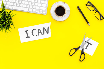 I can concept. Encourage youself. Sciccors cut off the letter t of written word I can't. Office desk. Yellow background top view space for text