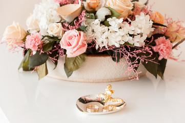 Wedding rings on a heart-shaped stand with a bouquet of flowers