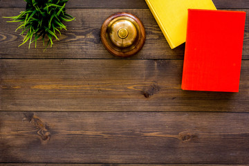 Library concept. Order the books. Hardback books near service bell and plant on dark wooden desk top view copy space