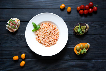 Spaghetti with tomato sauce, cheese and basil, bruschetta with humus, rucola, olives pasta, ham,...