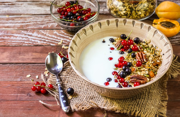 Obraz na płótnie Canvas Bowl of homemade granola with yogurt and fresh berries on wooden background from top view