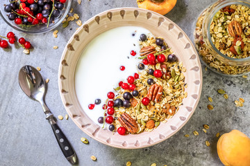 Bowl of homemade granola with yogurt and fresh berries on metallic background from top view