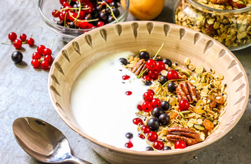 Bowl of homemade granola with yogurt and fresh berries on metallic background from top view