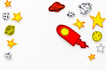 Space tourism concept. Drawn rocket or spaceship near stars, planets, asteroids on white background top view copy space