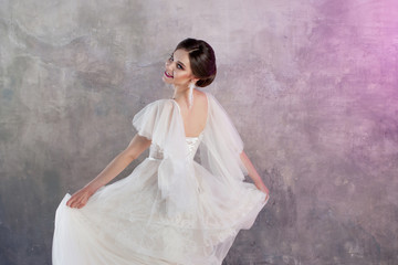 Fototapeta na wymiar Beautiful and stylish bride in wedding dress in Studio on grey textured background