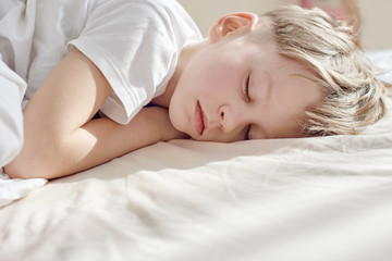 Portrait of cute young boy sweetly sleeping in bed