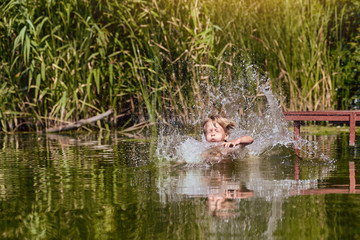 Young boy jumping, swimming and splashing in the river on summertime