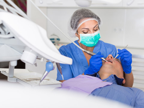 adult dentist checking teeth of patient