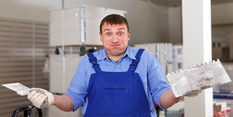 Surprised builder with plastering tools