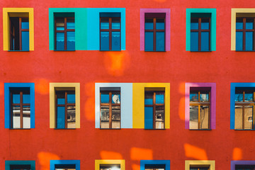 red facade with colorful window frames and light leaks