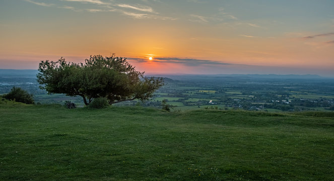 View of sunset from Crickley hill Gloucestershire with  a tree on the edge of the hillside in the foreground.