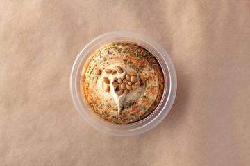 Hummus with pine nuts in the bowl with shadow on craft papper