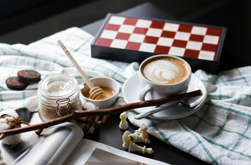 a cup of coffee and a chessboard on a black table. A thread of cotton, sugar cane, honey.